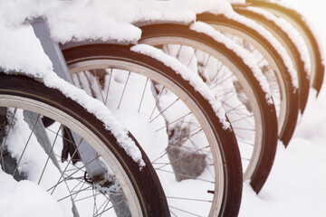 Rows of bicycles. Close-up shot of bicycle wheels under the snow. Winter season.