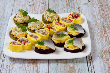 A festive snack for guests. canapes, rolls, fish and salad sandwiches. on a white plate. close up