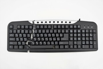 computer keyboard cut into two parts on a white background. keyboard is broken