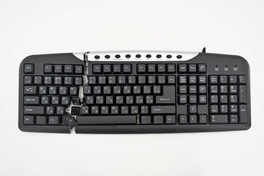 Computer Keyboard Cut Into Two Parts On A White Background. Keyboard Is Broken