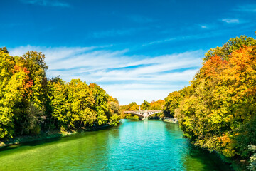 View on Isar river an colorful trees in autumn landscape in Munich