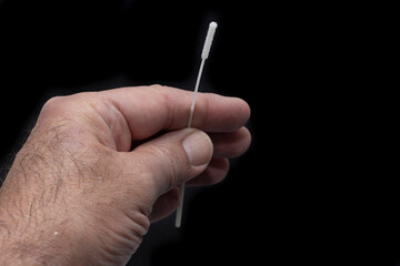 One hand holding the swab from the rapid sars-cov-2 antigen test card kit. Sold in pharmacies....