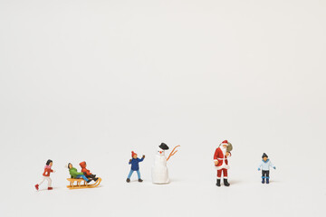 Christmas scene of miniature figures of kids and Santa Claus playing in the snow