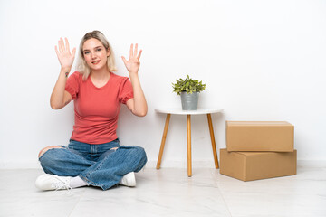 Young woman moving in new home among boxes isolated on white background counting nine with fingers