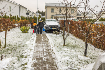 Fototapeta premium View of woman with children outdoor going to slide downhill on snowboards on bright winter day. Sweden. 