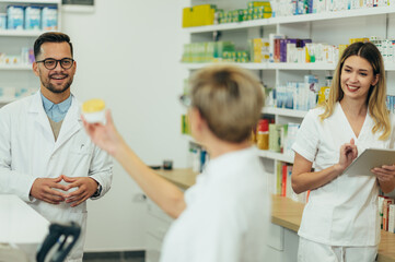 Male pharmacist working in a pharmacy with his female colleagues