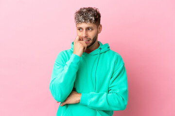 Fototapeta na wymiar Young handsome caucasian man isolated on pink background nervous and scared
