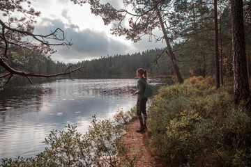 Woman hiking along footpath in the forest at lake in Tiveden National Park in Sweden.