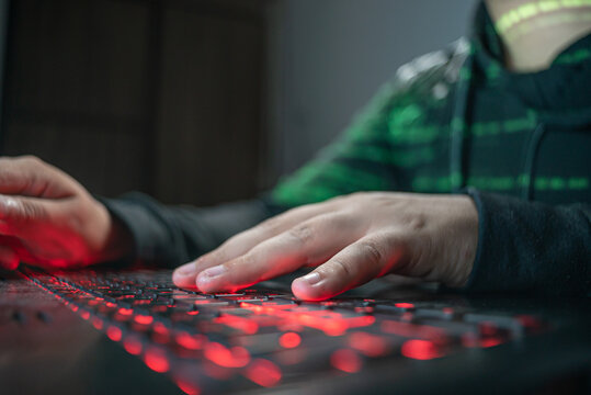 Hispanic man in front of his laptop with green coding lights on him