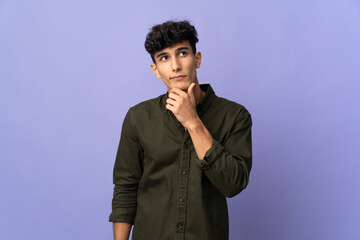 Young Argentinian man isolated on background and looking up