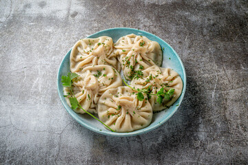 Georgian dumplings Khinkali with meat, greens and tomato spicy sauce Satsebeli against the background of a gray stone table