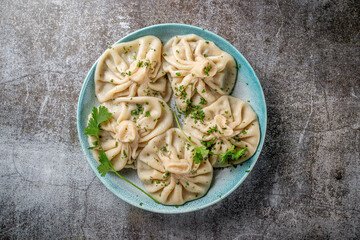 Georgian dumplings Khinkali with meat, greens and tomato spicy sauce Satsebeli against the background of a gray stone table
