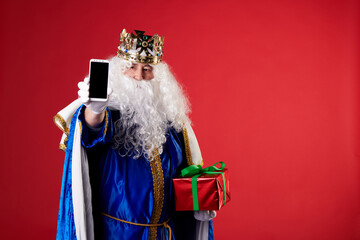 Magician King using a mobile phone on red background - obrazy, fototapety, plakaty