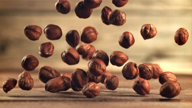 Hazelnuts fall on the table. On a wooden background.Filmed is slow motion 1000 frames per second.High quality FullHD footage