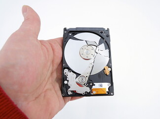 A technician's hand holding a broken laptop pc hard drive without a lid. Isolated on a white background. The concept of PC repair.