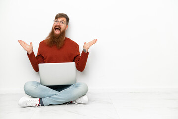 Young reddish caucasian man with laptop isolated on white background with shocked facial expression