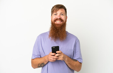 Young reddish caucasian man isolated on white background sending a message with the mobile