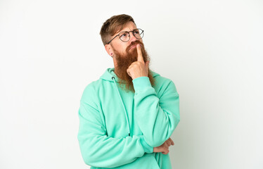 Young reddish caucasian man isolated on white background having doubts while looking up