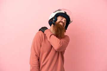 Young reddish caucasian man with a motorcycle helmet isolated on pink background suffering from pain in shoulder for having made an effort