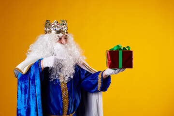 The Magician King with a present on a yellow background