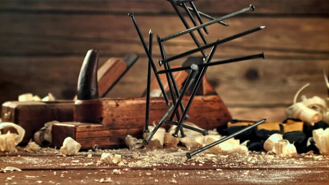 A bunch of nails fall on the table. On a wooden background. Filmed is slow motion 1000 frames per second.