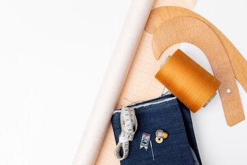 Denim fabric for sewing and sewing items - tailoring curve including pin, skein of thread, paper for sewing pattern.
