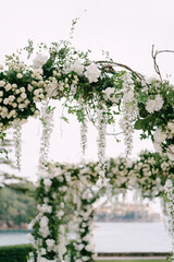 Wicker wedding arch decorated with roses, wisteria and green leaves