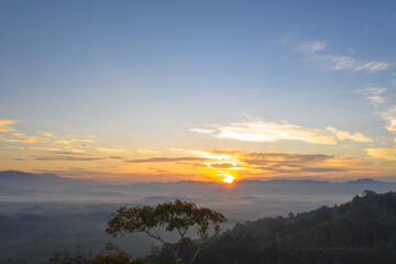 aerial view beautiful yellow sunrise above the mountain in phang Nga valley..slow floating fog blowing cover on the mountain look like as a sea of mist. .scenery golden sunrise at horizon background.