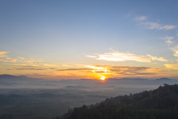 aerial view beautiful yellow sunrise above the mountain in phang Nga valley..slow floating fog blowing cover on the mountain look like as a sea of mist. .scenery golden sunrise at horizon background.