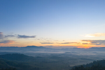 aerial view scenery sunrise above the mountain in tropical rainforest..slow floating fog blowing cover on the mountain look like as a sea of mist. .beautiful sunrise in the mist background.