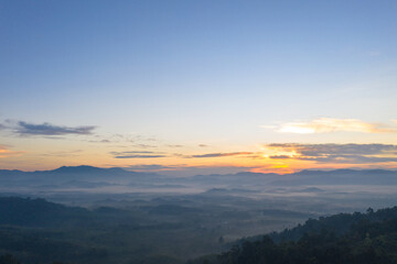 aerial view scenery sunrise above the mountain in tropical rainforest..slow floating fog blowing cover on the mountain look like as a sea of mist. .beautiful sunrise in the mist background.