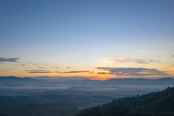 aerial view scenery sunrise above the mountain in tropical rainforest..slow floating fog blowing cover on the mountain look like as a sea of mist. .beautiful sunrise in the mist background.