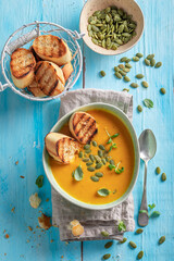 Yellow pumpkin soup with pumpkin seeds and crostini.