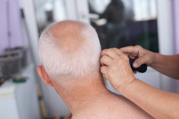 Haircut at home of an elderly man with gray hair. cutting the hair of a men indoor at home. har care