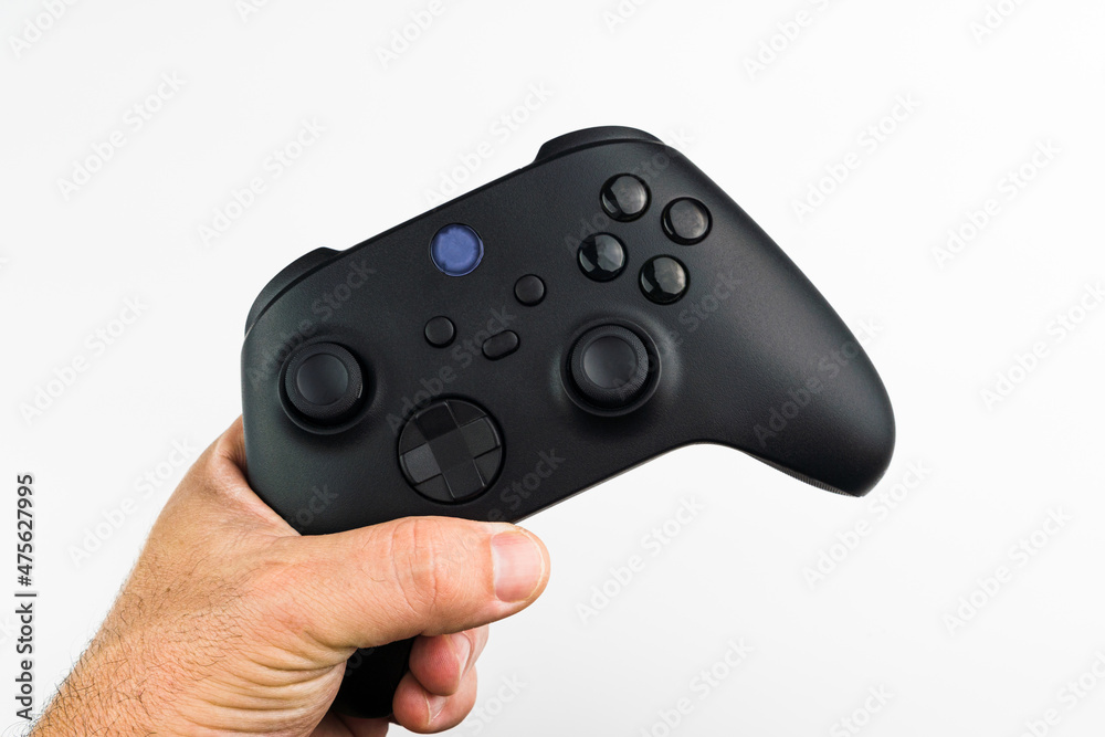 Wall mural man holding a next generation black game controller isolated on white background