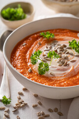 Red creamy carrot soup with parsley and sunflower seeds.