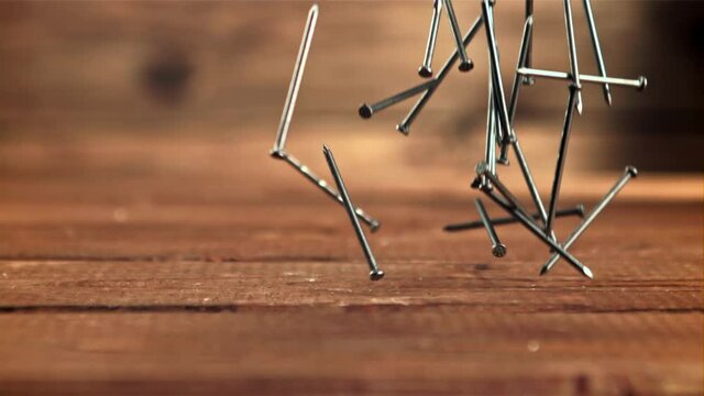 A lot of nails fall on the table. On a wooden background. Filmed is slow motion 1000 frames per second.High quality FullHD footage