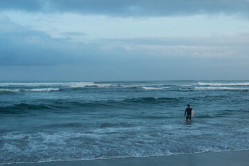 Fototapeta na wymiar A man ready to surf at Canggu beach Bali Indonesia.