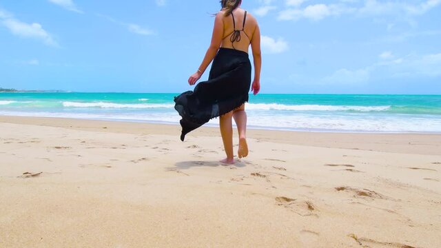 Woman walking to the sea on a beautiful beach of the brazilian northeast. Light sand, blue sea on a wonderful day. Cupe beach at Ipojuca PE, Brazil.