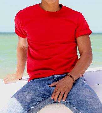 Guy In The Beach , Red T Shirt And Blue Jeans, Sea Background , Mock Up Free Space, Logo Presentation , Template For Print Design