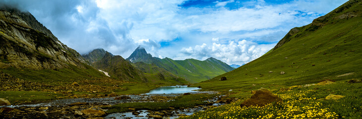 Naklejka na ściany i meble Panorama of the mountains. Scenic green meadow landscape in the Himalayas. Great Lake Trek in Kashmir, India. Mountains in Gangabal Lake vicinity. 