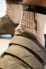 Close-up of a standing cyclist with dirty socks and shoes.