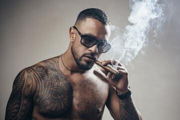 Portrait of handsome man smoking cigar. Tattooed man with cigar. Portrait of a mafia boss with a...