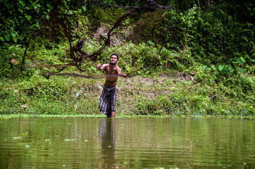 Fototapeta na wymiar The art of throwing a fishing net into the river or pond to catch fish. Long shot of a man catching fish with a fishing trap. Freeze motion of flying fishing net.