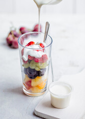 Fresh fruit salad with natural yoghurt pouring