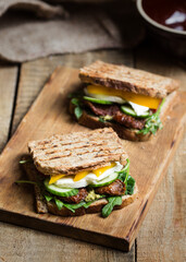 whole grain grilled sandwich with pesto, mozzarella cheese, dried tomatoes, cucumber, arugula and yellow bell pepper 