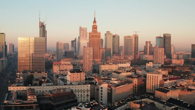 Slide and pan shot of high rise downtown buildings in sunrise sunlight. Morning panorama of city centre. Warsaw, Poland