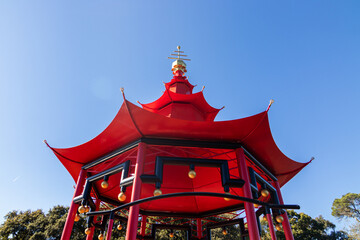 Low angle shot of a red gazebo against a clear blue sky