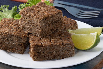 Kibbeh squares served with pieces of lemon. Selective focus.