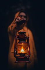 Vertical shot of a young man in a yellow hoodie holding a lantern - obrazy, fototapety, plakaty